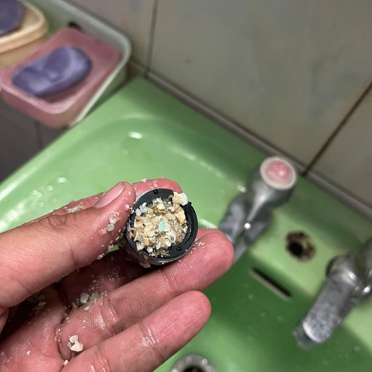 拆下的水龍頭起泡器濾網,卡滿白色與黃褐色的水垢碎屑