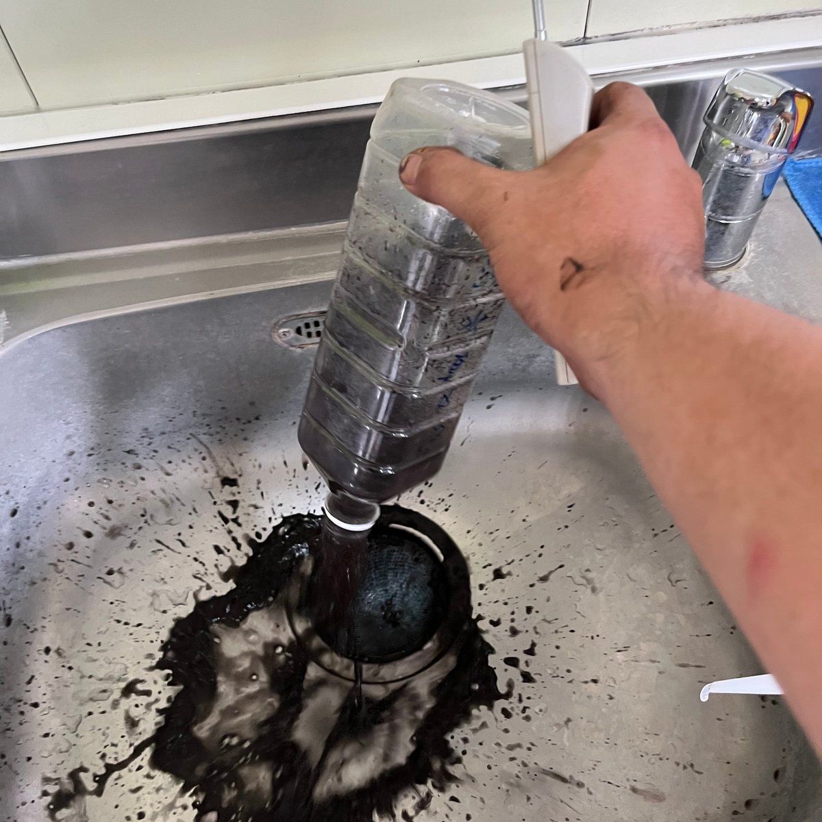 從水龍頭接出的整瓶深黑色濁水,倒進流理台的實拍畫面
